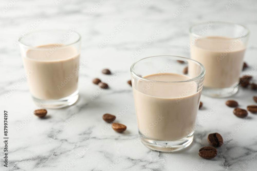 Coffee cream liqueur in glasses and beans on white marble table Coffee cream liqueur in glasses and beans on white marble table