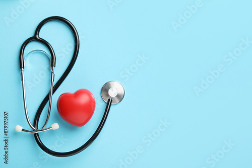 Принти на полотні Stethoscope and red heart on light blue background, top view