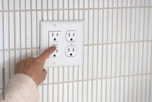 Testing GFCI outlet. Pressing test button on GFCI outlet. 