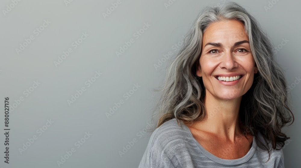 Middle-aged woman with a friendly smile, half-body shot against a solid light grey background, with copy space on the right side Middle-aged woman with a friendly smile, half-body shot against a solid light grey background, with copy space on the right side