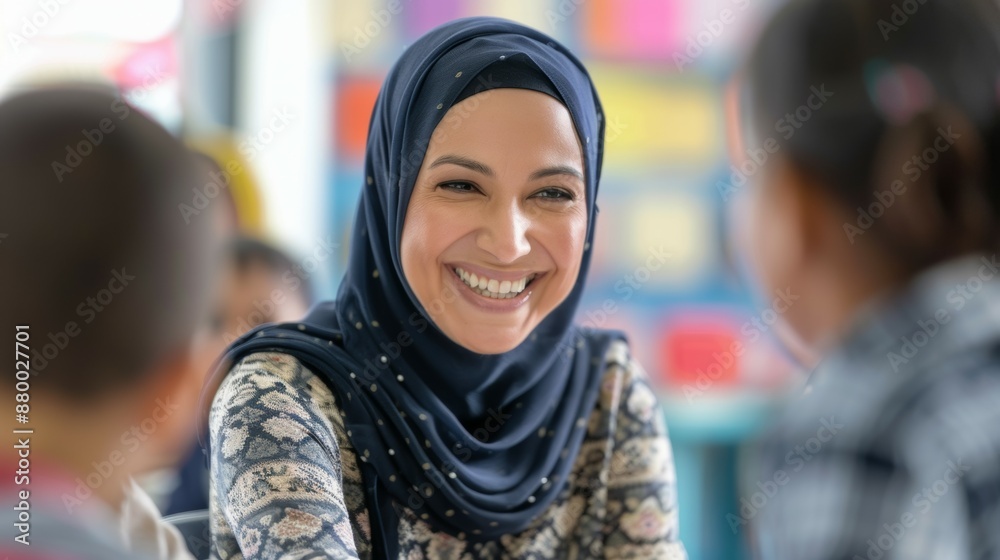 A smiling woman wearing a blue scarf is sitting at a table with children A smiling woman wearing a blue scarf is sitting at a table with children