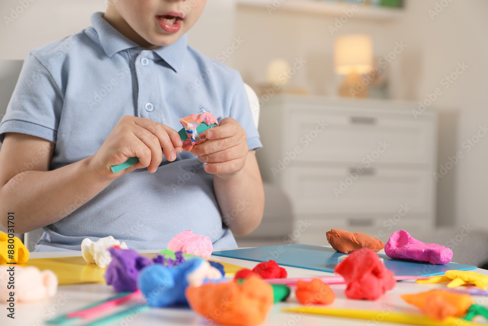 Little boy sculpting with play dough at table indoors, closeup Little boy sculpting with play dough at table indoors, closeup