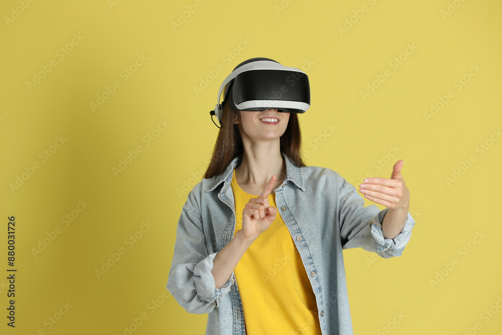 Smiling woman using virtual reality headset on yellow background Smiling woman using virtual reality headset on yellow background