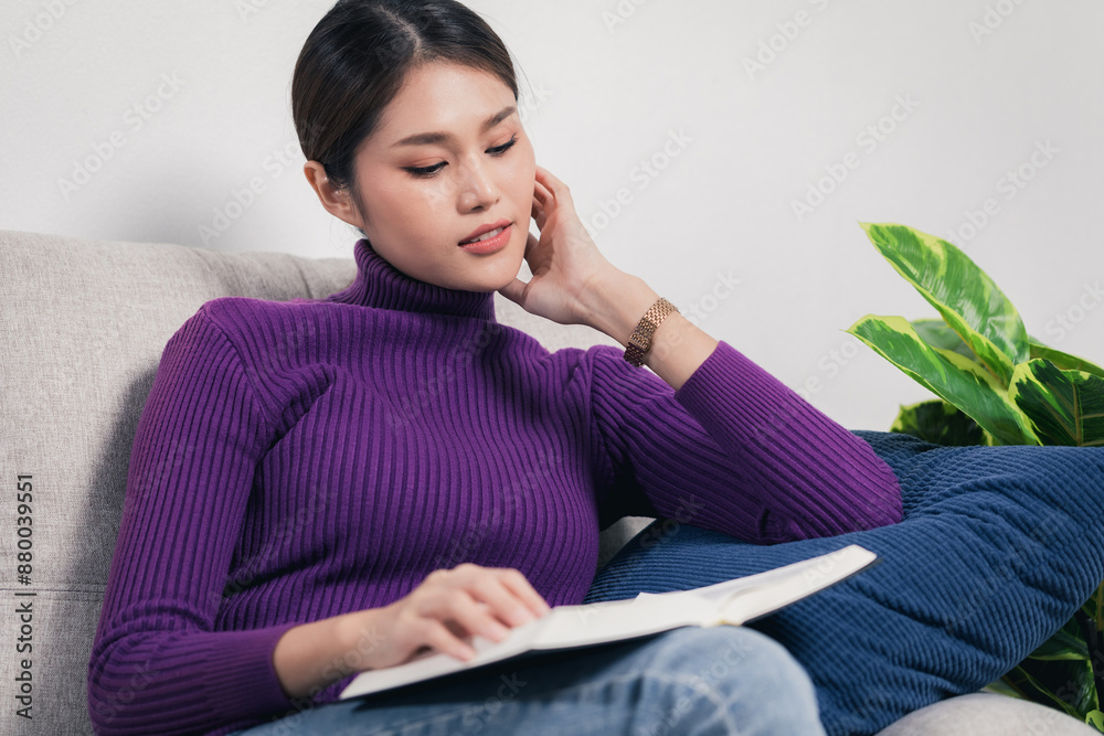 Young woman in purple sweater sits and reading book on the sofa at home. Young woman in purple sweater sits and reading book on the sofa at home.