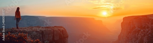 Woman standing on cliff edge at sunset