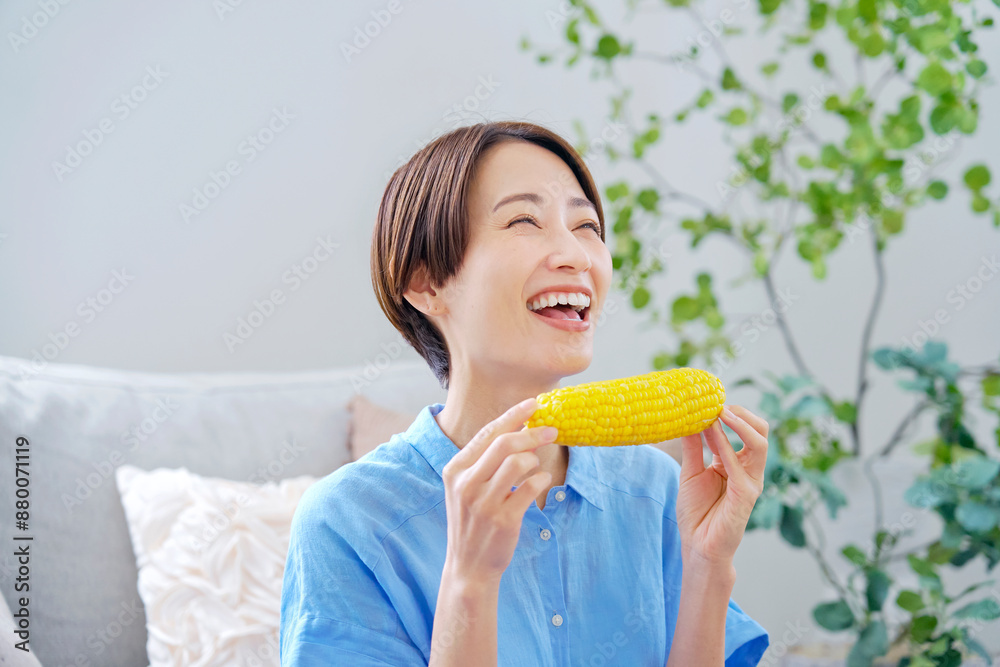 自宅でトウモロコシを食べる女性 自宅でトウモロコシを食べる女性