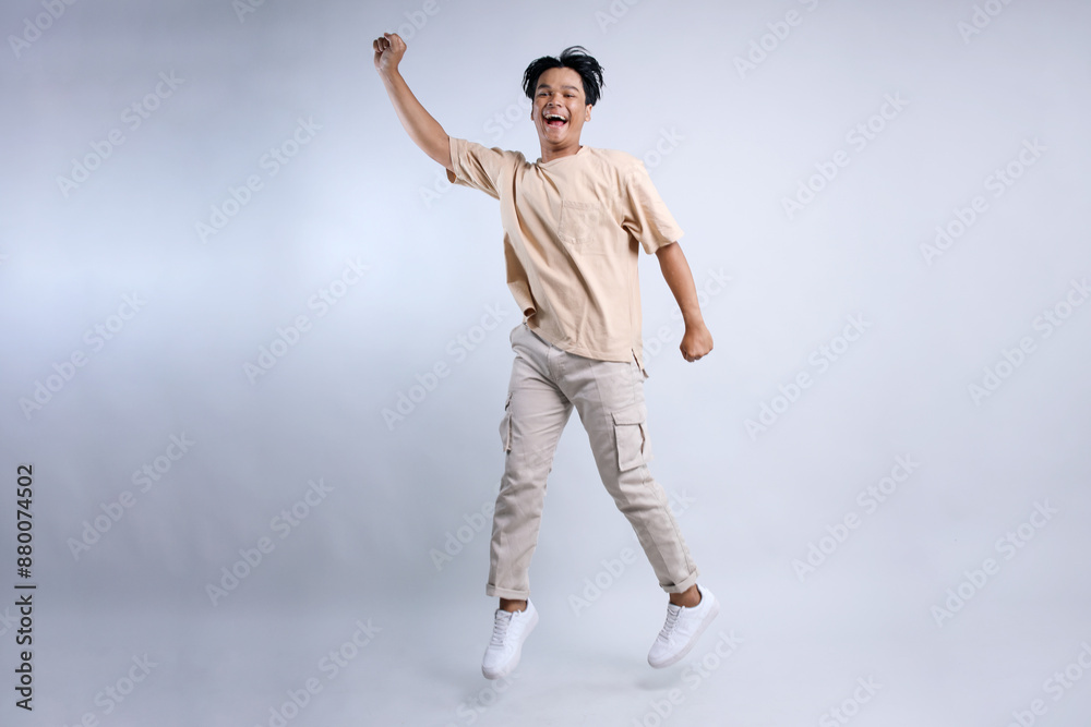 Front View Of Happy Young Asian Stylish Guy Jumping High And Showing Approved Gesture Front View Of Happy Young Asian Stylish Guy Jumping High And Showing Approved Gesture