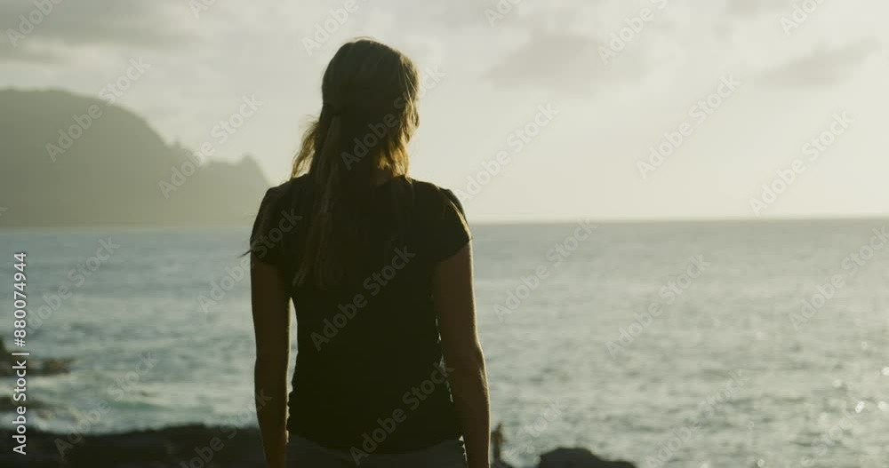Silhouette of beautiful woman looking around hawaiian shore at sunrise