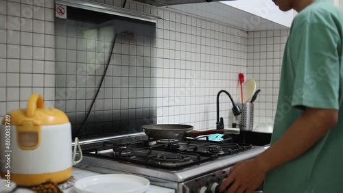 Man Sniffing Dish While Cooking Fried Chicken In Pan On Stove Preparing For Dinner At Home