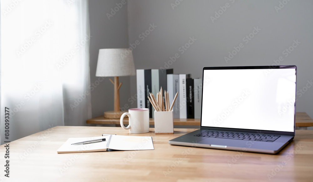 Fototapeta premium Open laptop with blank screen on a wooden desk in a kitchen room home office.