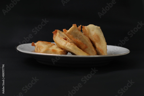 food made from thinly sliced ​​breadfruit coated in a wheat flour mixture then fried until dry and crispy. Fried breadfruit isolated on black background. photo
