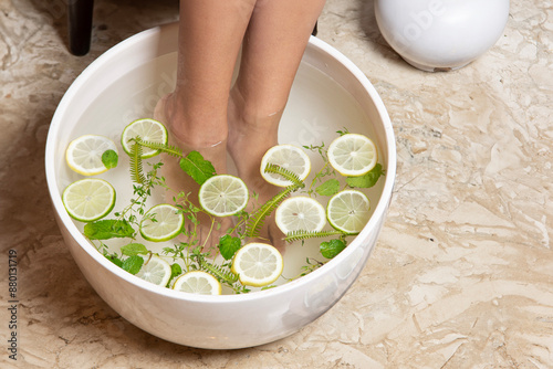  Woman took a bath with hot water, lemon, lemon and herbs for her feet. Homemade bath soak for dry foot skin photo