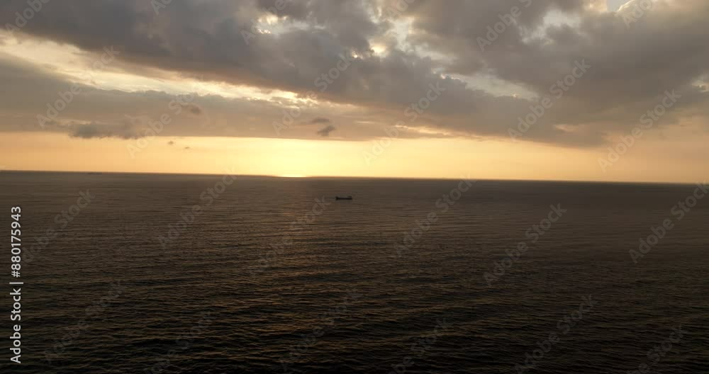 Drone dolly long shot toward freighter in open sea during scenic golden sunset Drone dolly long shot toward freighter in open sea during scenic golden sunset