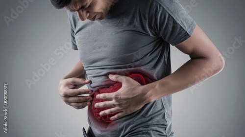 A man experiences abdominal pain, highlighting gut health issues. Emphasis on discomfort shown with red overlay. Neutral grey background. photo