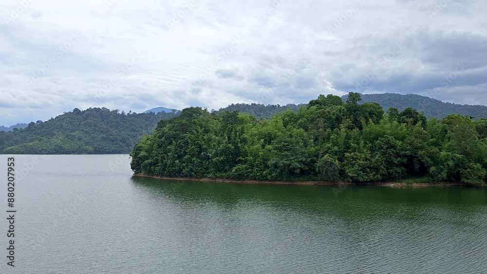Beautiful lake and green mountain natural scenery in Kuala Kubu Bharu, Selangor, Malaysia. A large river bank with island trees and clouds. Pan shot Beautiful lake and green mountain natural scenery in Kuala Kubu Bharu, Selangor, Malaysia. A large river bank with island trees and clouds. Pan shot