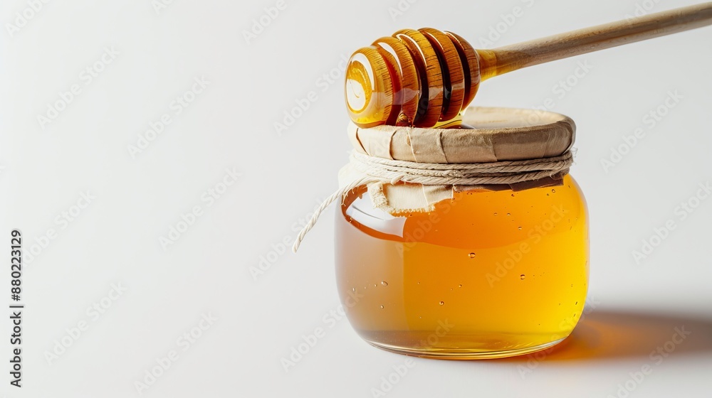 Minimalistic and elegant close up of golden honey jar with wooden dipper on white background Minimalistic and elegant close up of golden honey jar with wooden dipper on white background