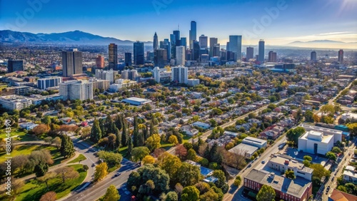 Panoramic bird's eye view of suburban Brentwood landscape blending into downtown Los Angeles's skyscraper-lined cityscape under clear blue sky. photo