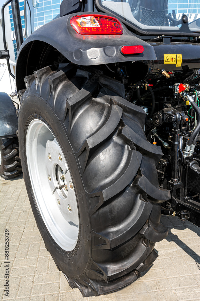Exhibition of agricultural machinery: a close-up of a wheeled tractor with large high-pass tires. Exhibition of agricultural machinery: a close-up of a wheeled tractor with large high-pass tires.