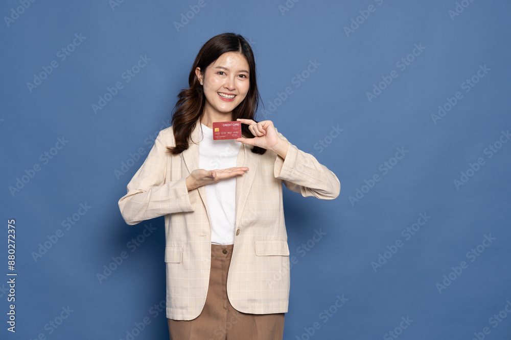 Young Asian business woman smiling, showing, presenting credit card for making payment or paying online business isolated on blue background Young Asian business woman smiling, showing, presenting credit card for making payment or paying online business isolated on blue background