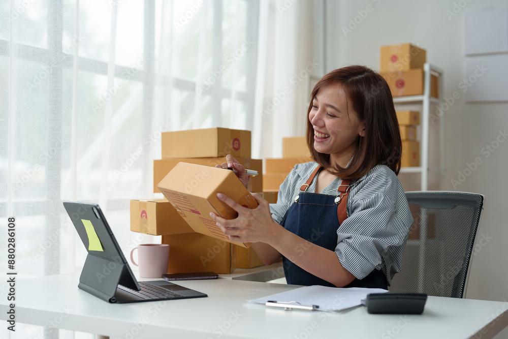 SME entrepreneurs, small businesses Online sales concept, happy Asian female business owner working on laptop computer and parcel boxes. Delivery of SME parcel boxes to customers Confirm order. SME entrepreneurs, small businesses Online sales concept, happy Asian female business owner working on laptop computer and parcel boxes. Delivery of SME parcel boxes to customers Confirm order.