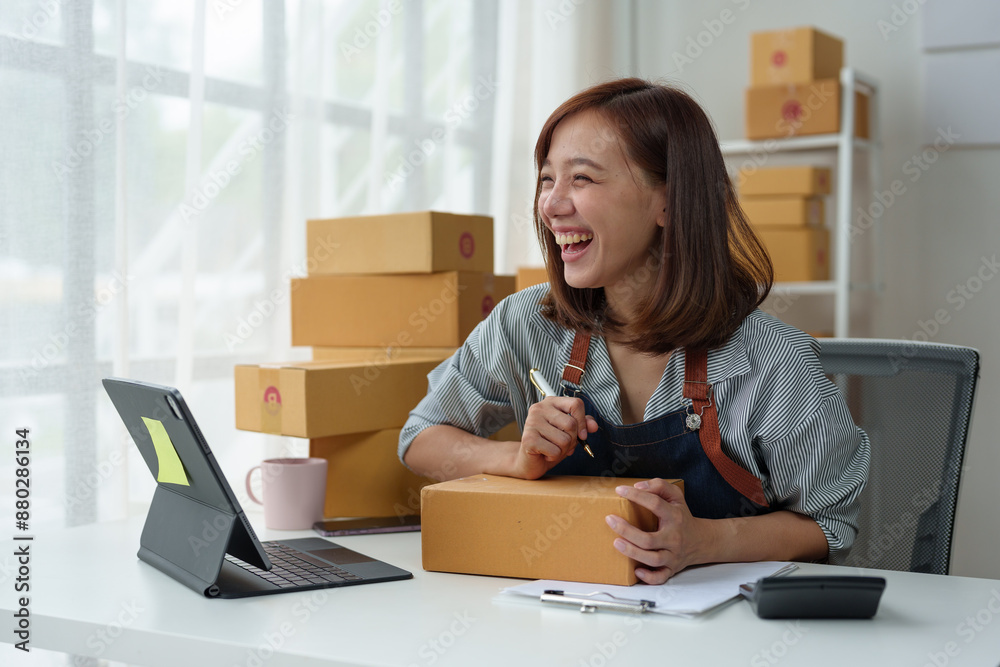 SME entrepreneurs, small businesses Online sales concept, happy Asian female business owner working on laptop computer and parcel boxes. Delivery of SME parcel boxes to customers Confirm order. SME entrepreneurs, small businesses Online sales concept, happy Asian female business owner working on laptop computer and parcel boxes. Delivery of SME parcel boxes to customers Confirm order.
