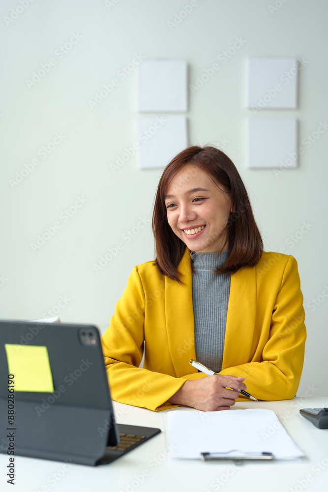 Asian businesswoman in yellow suit calculates company sales with calculator, laptop, smartphone in business communication with customers on desk in office technology concept. Asian businesswoman in yellow suit calculates company sales with calculator, laptop, smartphone in business communication with customers on desk in office technology concept.
