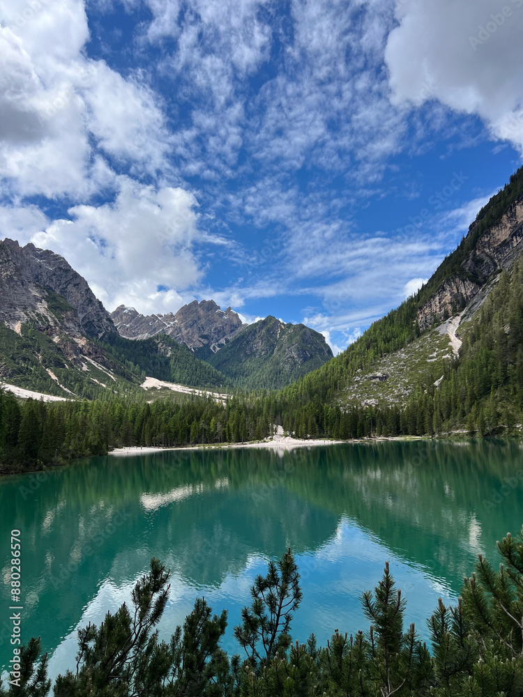 The photograph captures the breathtaking Dolomite Alps, where majestic peaks reach towards the sky, framing a crystal-clear lake at their base. The smooth surface of the lake reflects shades of the bl The photograph captures the breathtaking Dolomite Alps, where majestic peaks reach towards the sky, framing a crystal-clear lake at their base. The smooth surface of the lake reflects shades of the bl