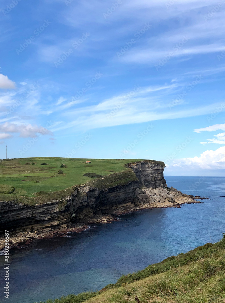 Acantilado verde en el mar cantábrico en la costa d España con el mar azul de fondo y el cielo lleno de nubes Acantilado verde en el mar cantábrico en la costa d España con el mar azul de fondo y el cielo lleno de nubes
