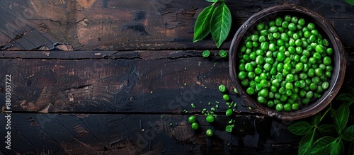 Top view of fresh organic raw green peas in a bowl with pea plants leaves on a dark wooden table background, ideal for healthy eating, vegan and vegetarian diets, with copy space image. photo