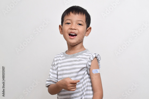 Asian boy shows his arm with bandage after virus vaccine. Child vaccination. Protect your child with vaccine concept. copy space