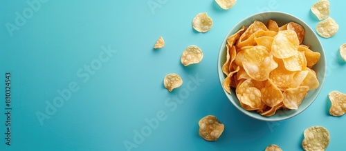 Top view of crispy potato chips in a bowl on a blue background with ample copy space image. photo