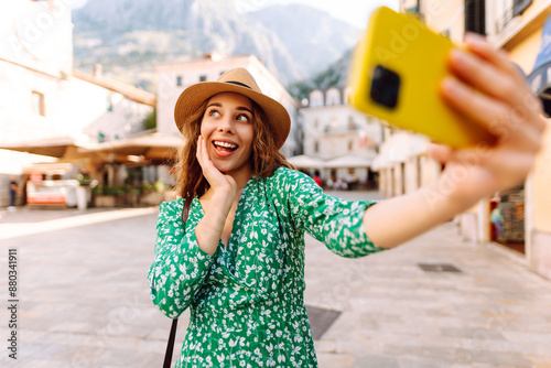 Happy woman takes a selfie photo on a smartphone against the background of old city. Travel and life in Italy.