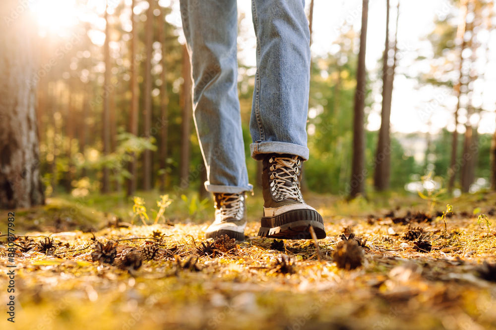 Feet of an adult wearing boots to travel walking in a green forest. Travel and hiking. The concept of nature, relaxation, walking. Feet of an adult wearing boots to travel walking in a green forest. Travel and hiking. The concept of nature, relaxation, walking.