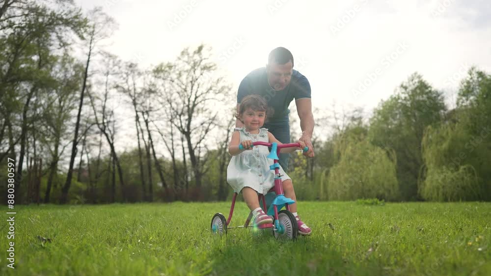 Father helps toddler ride together park. Happy family teaches toddler ride tricycle. Toddler learns tricycle with father help. father toddler riding tricycle together. Help tricycle together outdoors. Father helps toddler ride together park. Happy family teaches toddler ride tricycle. Toddler learns tricycle with father help. father toddler riding tricycle together. Help tricycle together outdoors.