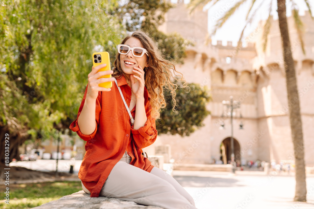 Fototapeta premium Happy woman tourist walking through the European street outdoors and making selfie. Travel, tourism, technology, blogging, communication concept.