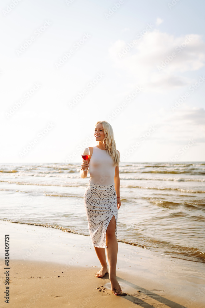 Beautiful model in elegant white dress at sunset with glass of wine. Travel, weekend, relax and lifestyle concept.
