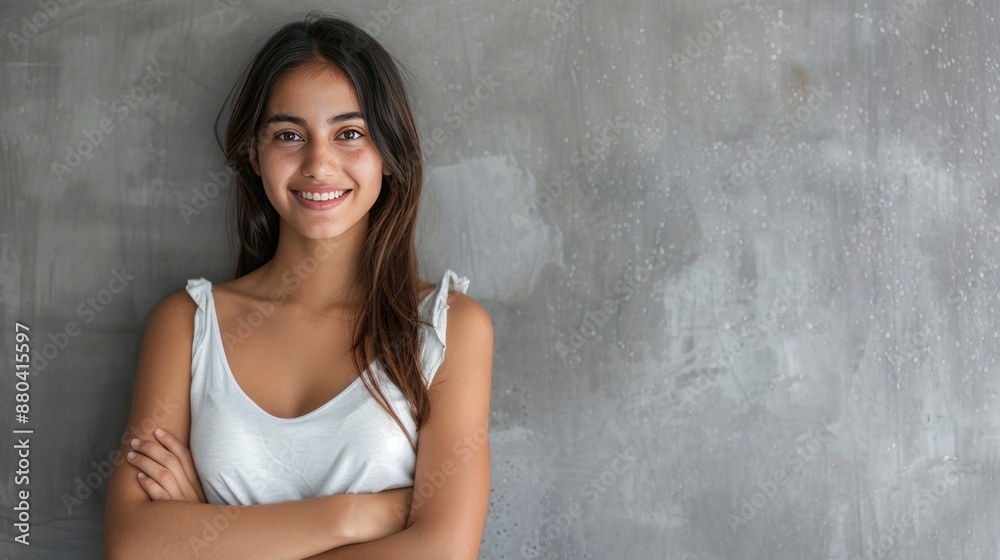 Portrait of a smiling young woman with arms crossed on grey background Portrait of a smiling young woman with arms crossed on grey background