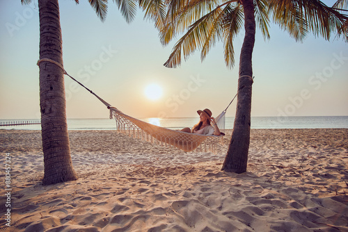 Εκτύπωση καμβά Calm woman with closed eyes chilling on a hammock on a tropical island among pal