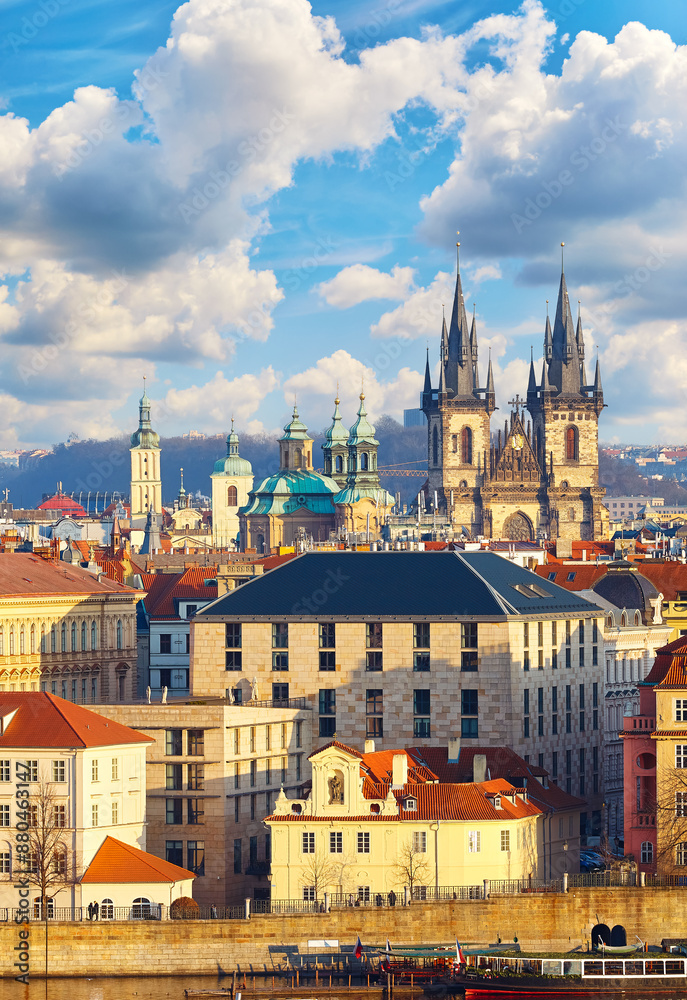 Naklejka premium High spires towers of Tyn church in Prague city (Church Our Lady before cathedral) urban landscape panorama with red roofs houses old town and blue sky clouds