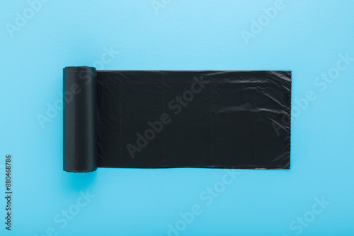 Obraz na plátně New dark black roll of plastic garbage bag on light blue table background
