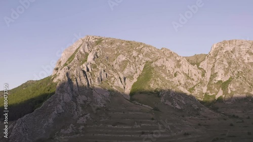 Early morning sunlight illuminates top half of Piatra Secuiului, Romania, near villages of near villages of Rimetea and Pietroasa photo