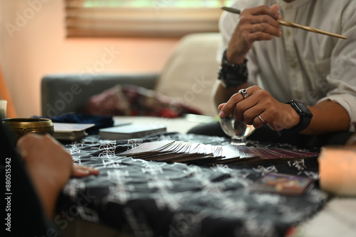 Fortune teller during a reading session talking to client at table with various spiritual items. Forecasting and divination concept