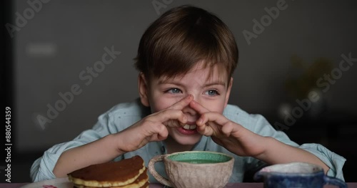 Little adorable boy drinking tea for breakfast with pancakes and apples at home. Cute weekend with sweet tasty food and emotional child. video footage 4k