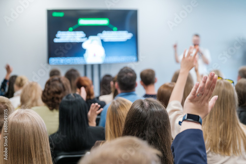 Engaged audience raising hands in a business presentation, indicating active participation and an interactive Q&A session. Ideal for concepts of learning, teamwork, and seminars.