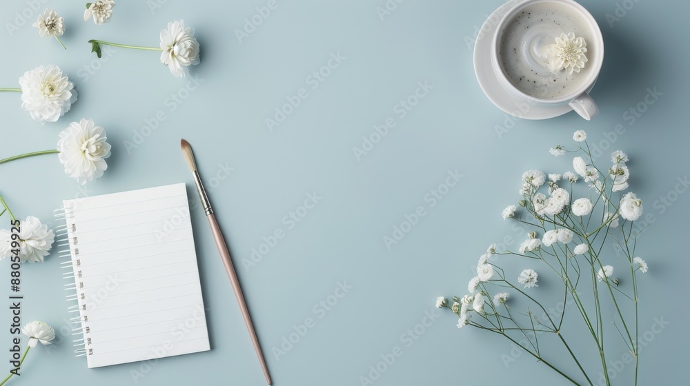 Obraz premium Flat lay of white flowers, a notebook, and a coffee cup on a blue background. Perfect for stationary, floral, or relaxation themes.
