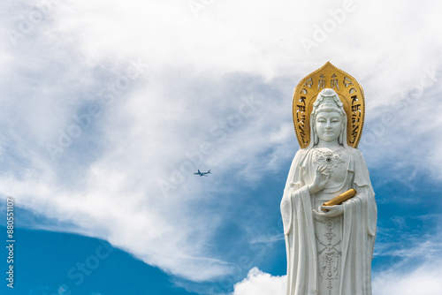 SANYA, HAINAN, CHINA Buddhist deity statue Guainin with a tourist plane in the sky