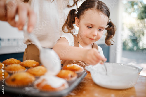 Baking, family and icing with mother, daughter and learning decoration in home kitchen. Food, kids and help with girl and mom happy with muffins, cupcakes and results for hobby bonding together