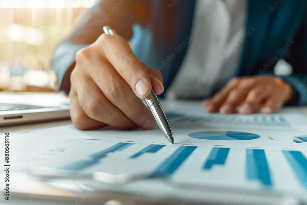 Close-up of a hand holding a pen, analyzing charts and graphs on a document, representing business and financial analysis. Close-up of a hand holding a pen, analyzing charts and graphs on a document, representing business and financial analysis.