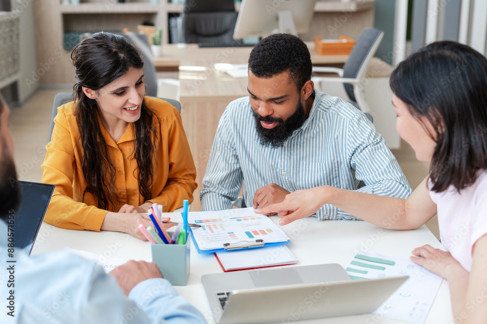 Diverse, multiethnic team of professionals analyzing charts and graphs during a productive meeting Diverse, multiethnic team of professionals analyzing charts and graphs during a productive meeting