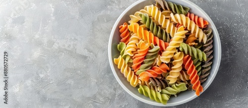 Panel kuchenny z motywem Top down view of a bowl filled with various colored raw fusilli pasta set against a grey backdrop This multicultural Italian cuisine ingredient is perfect for recipes and promotions with ample copy sp